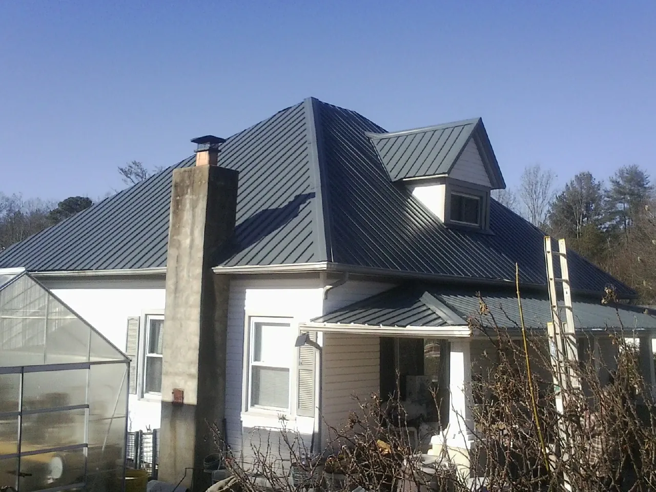 Dark blue standing seam metal roof on a white farmhouse with dormer — Slate & Tile Roof Repair by Roofing Brothers in Walbridge