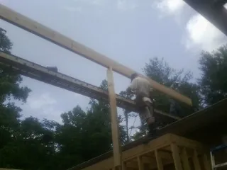 Carpenter setting a ridge beam over a new addition frame — Ice Dam Removal by Roofing Brothers in Walbridge