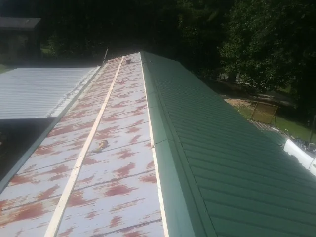 Old rusted panels beside newly installed green metal roofing — Wind Damage Roof Repair by Roofing Brothers in Walbridge