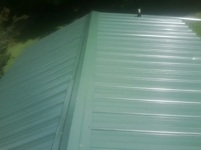 New green metal panels meeting at the ridge of a roof — Flat Roof Repair work by our crew in Walbridge