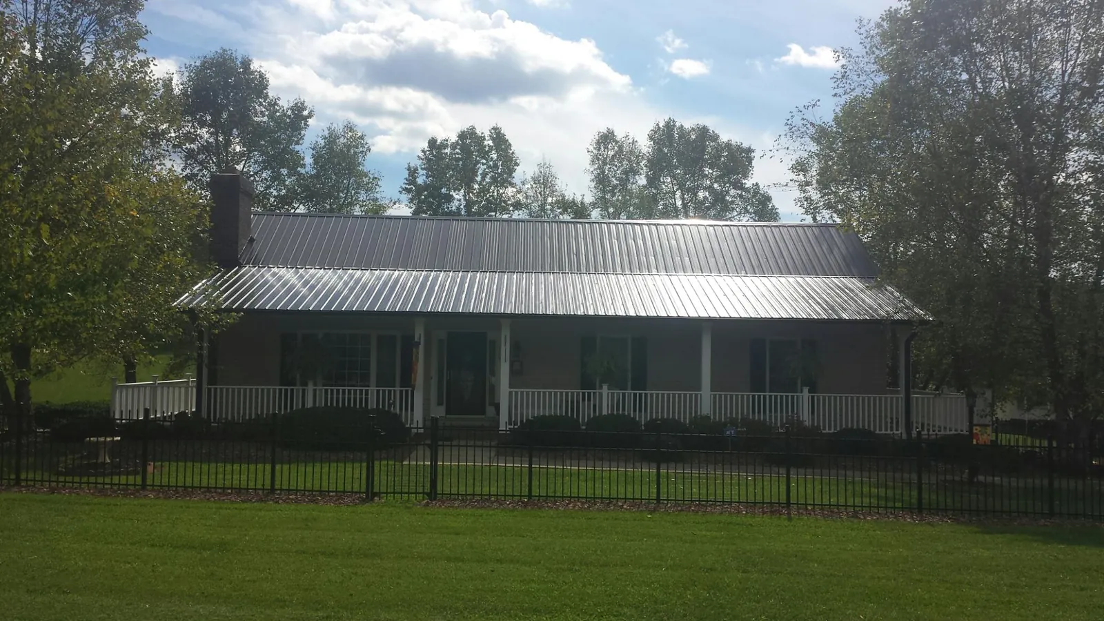 Gray metal roof on a brick ranch with a full width front porch — Gutter Guard Installation work by our crew in Walbridge