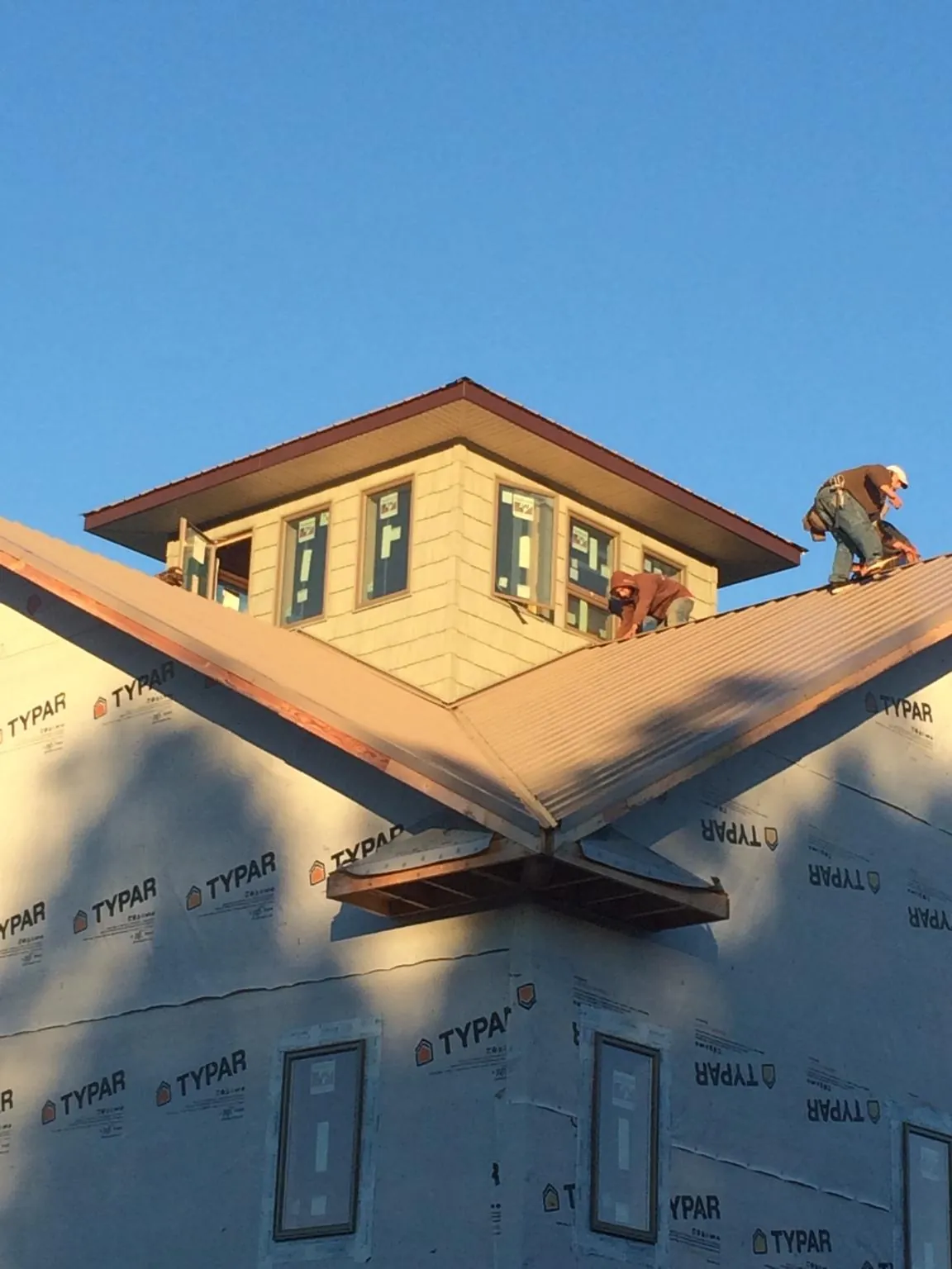 Roofers working around a rooftop cupola on a new metal roof at sunset — Roof Waterproofing in Walbridge by Roofing Brothers